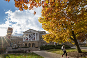 A student walking down Bascom Hill with Bascom Hall in the background on a fall day. 